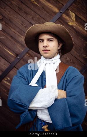 Jeunes hommes habillés comme soldats suédois du 17th siècle, histoire vivante. Un jeune homme dans un chapeau et un uniforme bleu pose avec une motte Banque D'Images