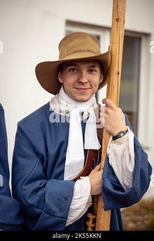 Jeunes hommes habillés comme soldats suédois du 17th siècle, histoire vivante. Un jeune homme dans un chapeau et un uniforme bleu pose avec une motte Banque D'Images