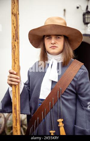 Jeunes hommes habillés comme soldats suédois du 17th siècle, histoire vivante. Un jeune homme dans un chapeau et un uniforme bleu pose avec une motte Banque D'Images