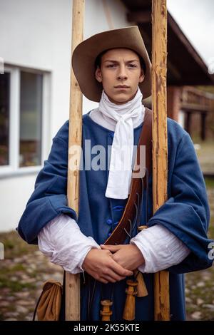 Jeunes hommes habillés comme soldats suédois du 17th siècle, histoire vivante. Un jeune homme dans un chapeau et un uniforme bleu pose avec une motte Banque D'Images