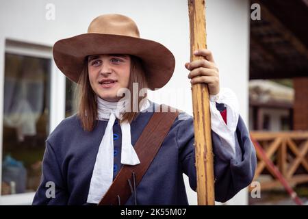 Jeunes hommes habillés comme soldats suédois du 17th siècle, histoire vivante. Un jeune homme dans un chapeau et un uniforme bleu pose avec une motte Banque D'Images