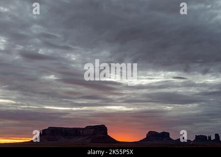Un coucher de soleil à couper le souffle sur des silhouettes de formations de grès dans Monument Valley Banque D'Images