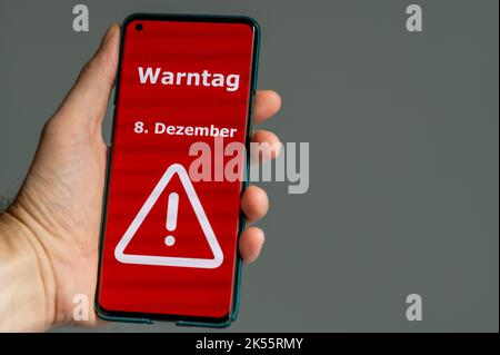 Symbole du jour d'avertissement national en Allemagne 2022. Main tient un téléphone portable avec le texte allemand 'Warntag 8. Dezember' (le jour d'avertissement le 8th décembre Banque D'Images