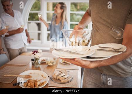 Déjeuner, famille et homme nettoyant les plats de la table après le repas. Nettoyez, emballez et éliminez les assiettes de la table du dîner après le déjeuner en famille Banque D'Images