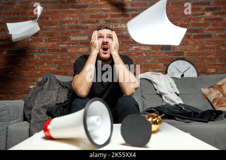 Homme d'affaires ou programmeur stressé travaillant à la maison ou au bureau avec inquiétude de vérifier l'heure à l'horloge, étant en retard, échéance. Mâle concentré Banque D'Images