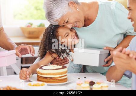 Hug, heureux et cadeau donnant d'une grand-mère et d'une fille avec gâteau d'anniversaire lors d'une fête. Le bonheur des personnes à un événement pour enfants à célébrer Banque D'Images