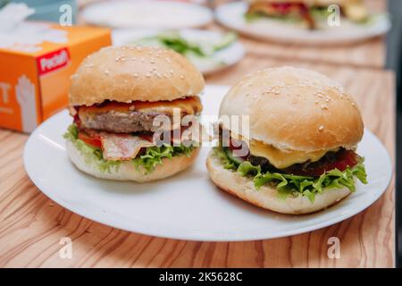 Hamburgers avec bœuf et légumes. Gros plan. Délicieux hamburgers en cours de cuisine. Hamburger avec sauce aux canneberges et hamburger avec sauce aux oignons. Banque D'Images