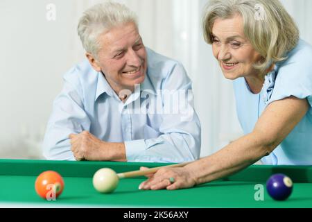 Joyeux couple senior jouant au billard à la maison Banque D'Images