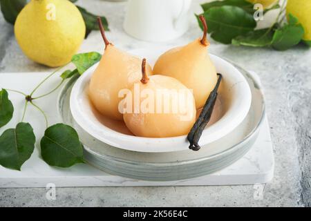 Poires. Poires pochées au sirop. Dessert traditionnel en tranches dans une assiette blanche avec des feuilles et à la maison sur un fond clair. Délicieux dessert pour Banque D'Images