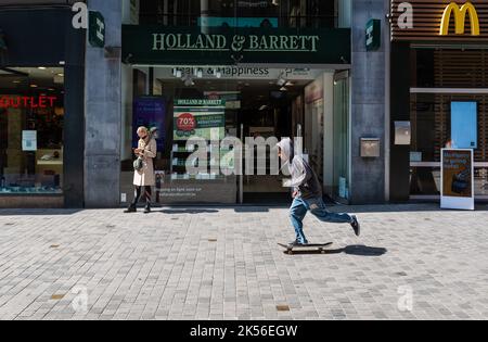 Centre ville de Bruxelles, région de la capitale de Bruxelles - Belgique - 05 01 2021 Black boy conduisant un skateboard en face de la pharmacie Holland et Barrett Banque D'Images