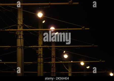 Les feux de rue et les câbles de tram sont sur fond de ciel sombre. Photo abstraite de nuit urbaine Banque D'Images