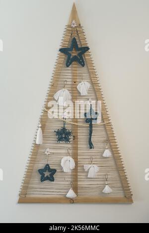 Anges blancs et flocons de neige bleus étoiles décorations macramé. Sapin de Noël en bois fait à la main avec branches à cordes sur le mur. Décoration de vacances avec macrame Banque D'Images