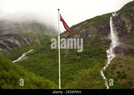 Drapeau norvégien (pennon) soufflant dans le vent, avec une cascade en arrière-plan. Montagnes à Briksdalsbreen, Jostedalsbreen. Pennant de Norvège / pendentif. Banque D'Images