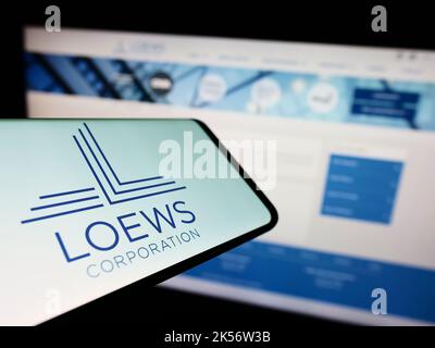 Téléphone mobile avec le logo du conglomérat américain Loews Corporation à l'écran devant le site Web de la société. Effectuez la mise au point au centre-droit de l'écran du téléphone. Banque D'Images