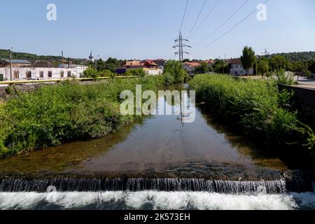 Vue sur la rivière Cerna passant par la ville de Hunedoara, Transylvanie, Roumanie. Les pôles de puissance sont réfléchis dans l'eau. Banque D'Images