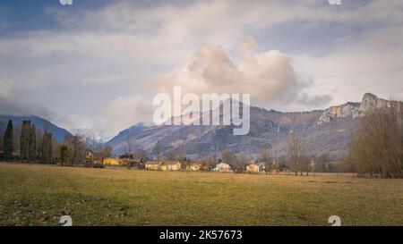 Ville de Surba se cachant derrière des arbres au pied des Pyrénées avec des sommets enneigés en arrière-plan, Tarascon sur Ariege, France Banque D'Images