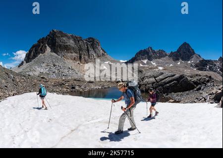 France, Savoie, Valmeinier, massif du Thabor, trek autour du Thabor, au col de Chaval blanc, groupe de randonneurs sur un petit lac partiellement couvert de neige, les sommets du Chaval blanc, le pic du Thabor (3058m) et Tabor Banque D'Images