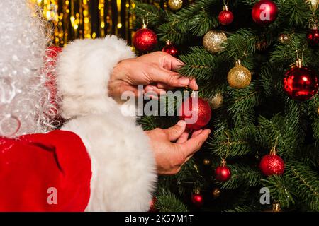 Vue rognée du père noël barbu décorant l'arbre de noël avec des boules, image de stock Banque D'Images