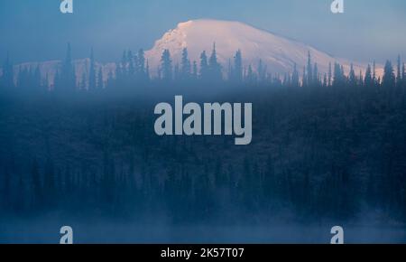 Brouillard et brume tôt le matin sur Twin Lakes à Wrangell-St. Parc national et réserve d'Elias en Alaska. Le mont Sanford s'élève au-dessus des arbres. Banque D'Images