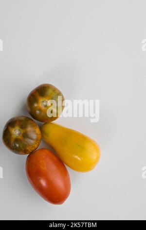 une jaune une prune et deux tomates tigrées rouges Banque D'Images