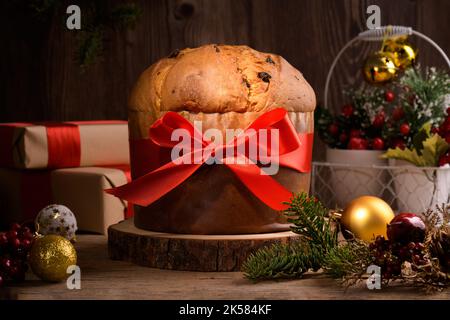 Gâteau de Noël italien traditionnel Panettone avec noeud rouge et décoration festive sur fond rustique en bois. Un pain de levain fait maison est un panettone Banque D'Images