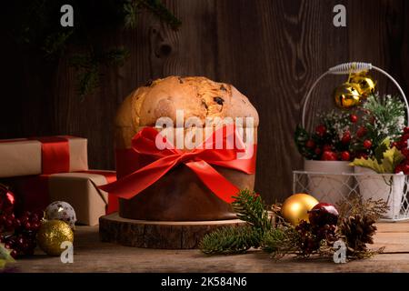 Gâteau de Noël italien traditionnel Panettone avec noeud rouge et décoration festive sur fond rustique en bois. Un pain de levain fait maison est un panettone Banque D'Images