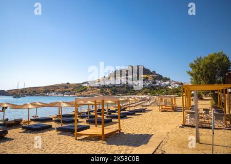 Vue sur la plage de Lindos avec la ville et l'Acropole en arrière-plan, l'île de Rhodes, la Grèce, l'Europe. Banque D'Images