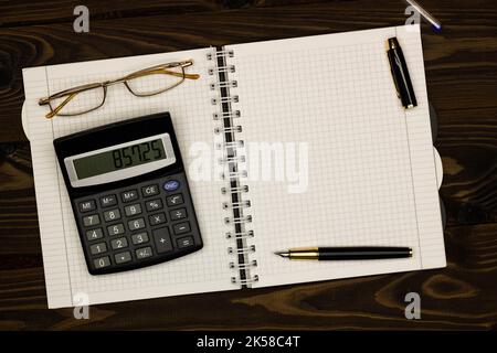 Table de bureau avec vue sur le dessus. Rapport financier. Pose à plat. Espace de travail avec fournitures de bureau, feuille de papier vide, stylo, lunettes, calculatrice sur le Banque D'Images