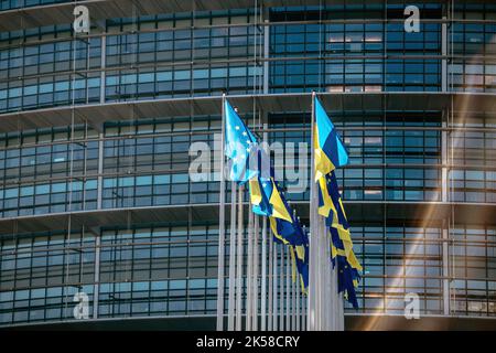 Strasbourg, France - 8 mars 2022 : le drapeau ukrainien passe à côté du drapeau de l'Europe et de tous les drapeaux des membres de l'Union européenne devant le bâtiment du Parlement la Russie poursuit son assaut sur les grandes villes ukrainiennes une semaine après le lancement d'une invasion à grande échelle du pays Banque D'Images