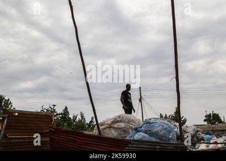 Kisumu, Kenya. 04th octobre 2022. Un homme est vu debout sur un tas de bouteilles en plastique dans un centre de collecte des déchets en plastique à Kisumu. Des militants et des groupes environnementaux au Kenya et dans d'autres parties du monde ont dénoncé la société Coca-Cola qui serait nommée sponsor du sommet climatique de cette année, la CdP 27, qui se tiendra en novembre en Egypte. Crédit : SOPA Images Limited/Alamy Live News Banque D'Images