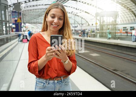 Un voyageur brésilien souriant et attrayant achète un billet en ligne avec un smartphone à la gare. Copier l'espace. Banque D'Images