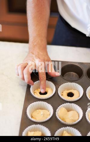 Ajoutez une petite surprise. Gros plan d'un boulanger mettant un centre de chocolat dans un plateau Banque D'Images