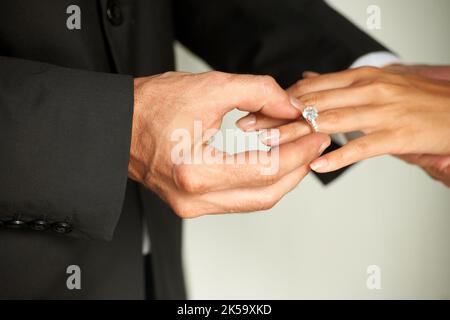 Je dis..vue courte d'un marié glissant un anneau sur son doigt de mariée. Banque D'Images