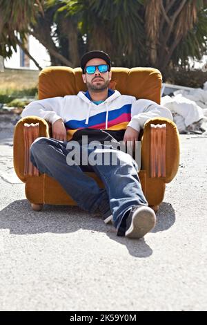 Mon style définit qui je suis. Un gars avec attitude assis sur un canapé dans la rue. Banque D'Images