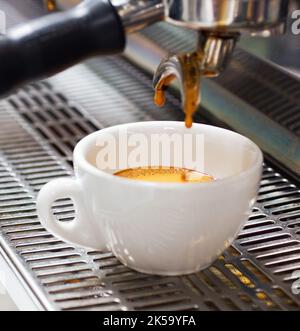 Caféine fixe presque prêt. Gros plan d'une machine à espresso avec une tasse de café. Banque D'Images