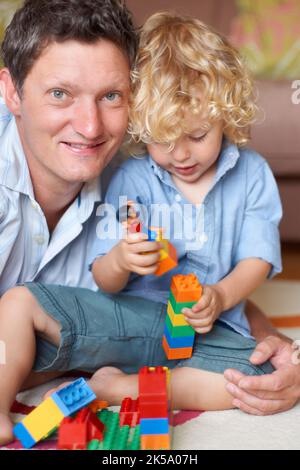 C'est un super tout-petit. Portrait d'un père allongé avec son fils qui joue avec des blocs de construction. Banque D'Images