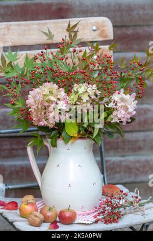 bouquet d'automne de fleurs d'hortensia, de hanches roses et de feuilles d'érable dans un vase rustique Banque D'Images