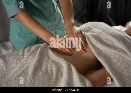 Gros plan des mains massant l'abdomen de la femme. Thérapeute appliquant une pression sur le ventre. massage corporel, drainage lymphatique, procédures manuelles. Femme Banque D'Images