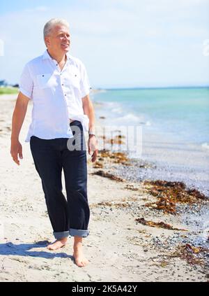 Admirez la beauté de l'océan. Un homme âgé marchant pieds nus sur le rivage. Banque D'Images