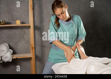 Massage des pieds dans le centre médical, masseuse faisant un massage des pieds pour la femme Banque D'Images