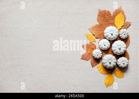 Arrière-plan artisanal d'automne avec citrouilles décoratives en argile et feuilles d'automne en bois. Citrouilles décoratives plates sur fond de tissu naturel Banque D'Images