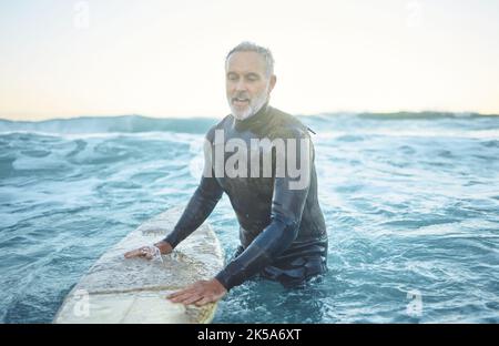Surf, océan et homme senior nageant avec planche dans les vagues bleu de mer et le ciel mockup matin. Sports, fitness et aventure surfer dans l'eau tropicale pour Banque D'Images