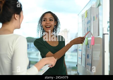 Jeune femme créative partageant des idées stratégie d'affaires, expliquant les nouvelles stratégies sur le tableau blanc à l'employé Banque D'Images