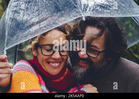 L'amour entre l'homme adulte et la femme s'amusant ensemble sous un parapluie transparent le jour de pluie de l'activité de loisirs en plein air. Couple heureux dans relationsh Banque D'Images