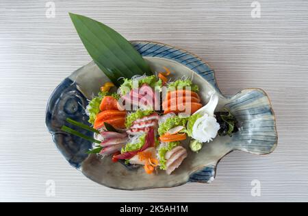 Sashimi mori, ensemble de sashimi mélangé servi dans une assiette en céramique décorée de laitue verte. Buffet de cuisine japonaise. Choix du chef : saumon, hamachi, Ika, Tako Banque D'Images