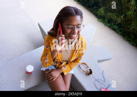 Vue en grand angle de la jeune femme afro-américaine qui parle au téléphone et rit. Copier l'espace. Banque D'Images