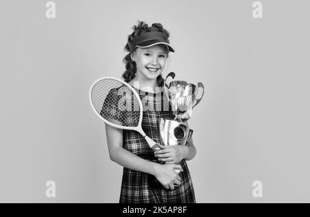 le succès sportif. une jeune fille heureuse de vêtements de sport a remporté le prix. coupe de championnat. une raquette de badminton réussie pour enfant. un joueur de tennis pour enfant est champion. h Banque D'Images