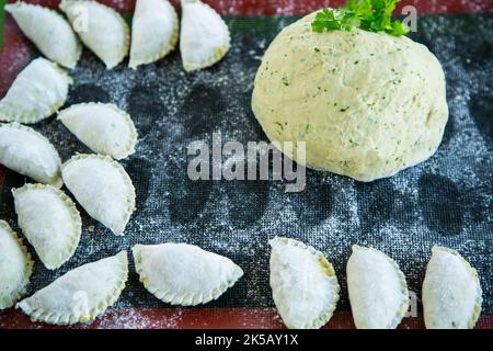 Pâte verte brute avec persil, aneth avec boulettes crues. Boulettes crues sur une table en bois. Banque D'Images