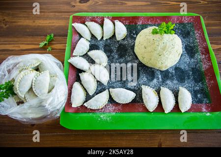 Boulettes de pâte verte crue avec persil, aneth. Boulettes crues dans un sac sur une table en bois. Banque D'Images