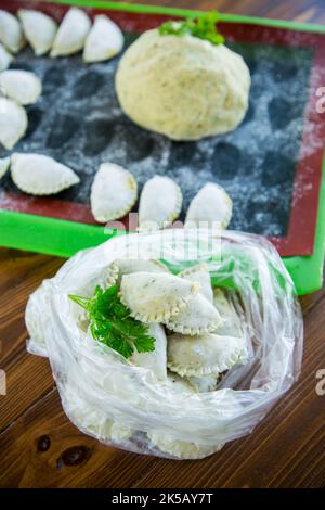 Boulettes de pâte verte crue avec persil, aneth. Boulettes crues dans un sac sur une table en bois. Banque D'Images